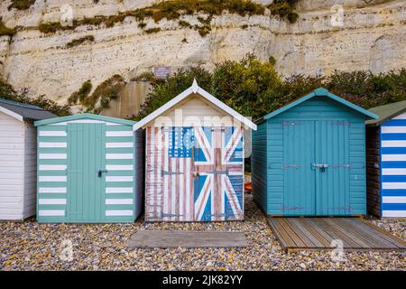 Eine Reihe von Strandhütten am Fuße der Kreidefelsen bei Beer, einem kleinen Küstendorf an der Lyme Bay an der Jurassic Coast of East Dorset, Südwestengland Stockfoto