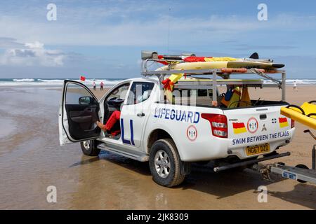 Ein RNLI Surf Rescue LifeGuard Pickup Patrol Truck sitzt am Strand und beobachtet Strandnutzer und Schwimmer in Not. Stockfoto