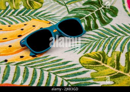 Blaue Sonnenbrille auf einem Hawaii-Handtuch. Stockfoto