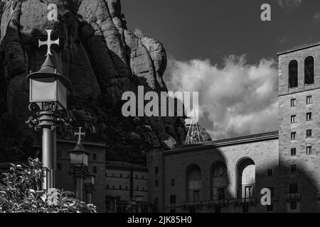 Schwarz-weiße Ansicht der Fassade des Klosters von Montserrat am späten Nachmittag. Die felsigen Reliefs des Montserrat-Gebirges erheben die Spiritua Stockfoto