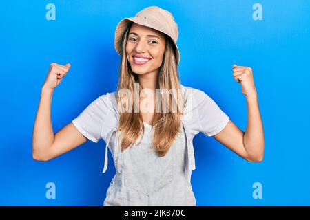 Schöne hispanische Frau mit Explorer Hut schreiend stolz, feiert Sieg und Erfolg sehr aufgeregt mit erhobenen Armen Stockfoto