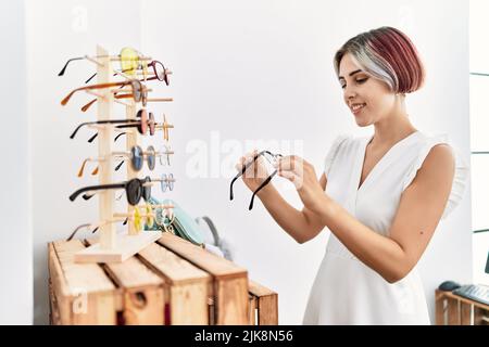 Junge kaukasische Kundin, die lächelt, freut sich über die Wahl der Brille im optischen Laden. Stockfoto