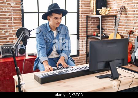 Junger nicht-binärer Musiker, der Klavier-Keyboard im Musikstudio spielt Stockfoto