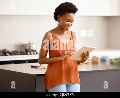 Planung meiner Mahlzeit Vorbereitung. Eine junge Frau mit einem Tablet zu Hause. Stockfoto