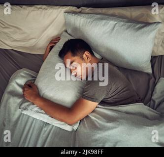 Nicht alle Wunden sind an der Oberfläche zu sehen. Ein junger Mann liegt im Bett und sieht unglücklich zu Hause aus. Stockfoto