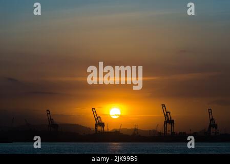 Industriekrane am Horizont mit Sonnenuntergang Stockfoto