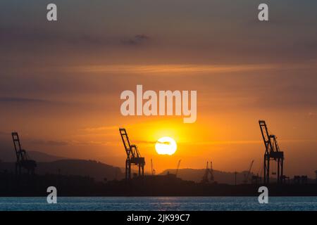 Industriekrane am Horizont mit Sonnenuntergang Stockfoto