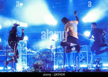 Jump Shot mitten in der Luft von Leon Locksmith Rolle aka DJ Locksmith (R2) mit der britischen Trommel- und Bassband Rudimental, die live auf der Bühne mit verschiedenen Gastsession-Musikern beim Camp Beestival Familienfestival auftrat. Rudimental wurden 2013 für den Mercury Prize nominiert und gewann mehrere Auszeichnungen, darunter den Brit Award und den MOBO Award für das beste Album. Rudimental erhielt auch Nominierungen bei den MTV Europe Music Awards für den besten neuen Act und den besten britischen und irischen Act. Rudimental hat mehrere Platin-Auszeichnungen für Rekordverkäufe in mehreren Ländern erhalten, darunter im Vereinigten Königreich und Australien. Stockfoto