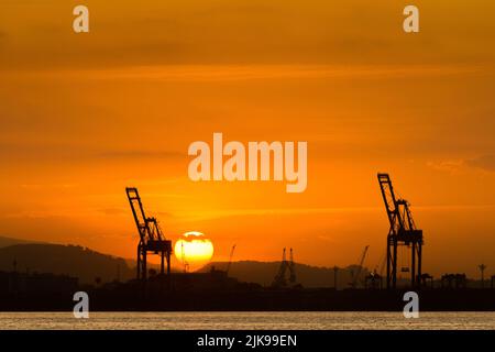 Industriekrane am Horizont mit Sonnenuntergang Stockfoto