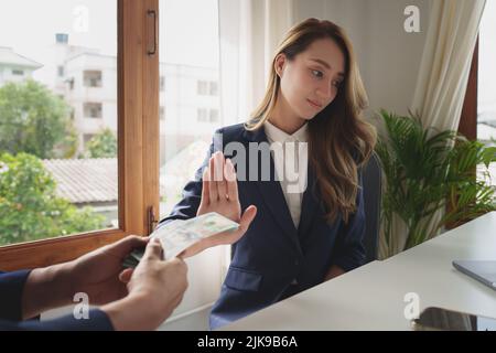 Frau, die das Angebot des Auftragnehmers von Schwarzgeld im Austausch für eine Genehmigung für den Deal ablehnt. Konzepte von Korruption und Bestechungsbekämpfung. Stockfoto