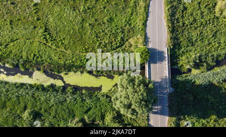 Brücke über den Fluss, der durch die Felder und Wiesen schießt von einer Drohne, Ukraine fließt Stockfoto