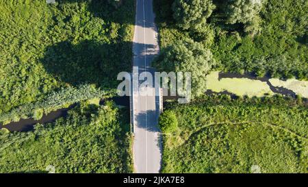 Brücke über den Fluss, der durch die Felder und Wiesen schießt von einer Drohne, Ukraine fließt Stockfoto