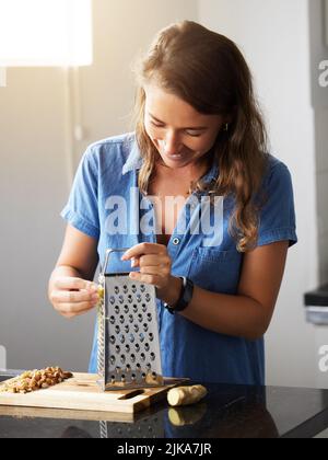 Wenn Sie es leid sind, von Neuem zu beginnen, hören Sie auf aufzugeben. Eine junge Frau bereitet zu Hause eine gesunde Mahlzeit zu. Stockfoto