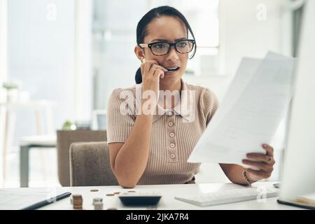 Eine schlechte Budgetierung kann zu mehr finanziellem Stress führen. Eine junge Geschäftsfrau schaut gestresst aus, während sie die Finanzen in einem Büro berechnet. Stockfoto