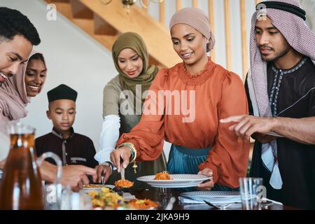 Füllen Sie Ihren Teller. Eine muslimische Familie serviert Mittagessen für sich. Stockfoto