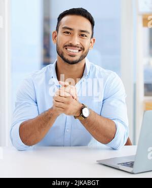 Dankbar für alle Geschäftsmöglichkeiten. Ein junger Geschäftsmann, der bei der Arbeit an einem Schreibtisch sitzt. Stockfoto