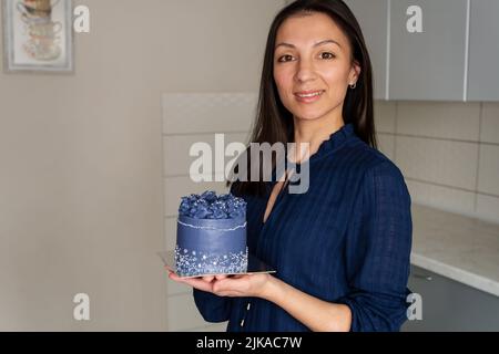 Junge Bäckerin mit Süßigkeiten, die einen Kopierplatz auf einer Handfläche zeigen. Stockfoto