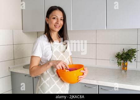 Junges Mädchen, das Eier in einem Bogen peitschend. Porträt der Konditorin Frau Stockfoto