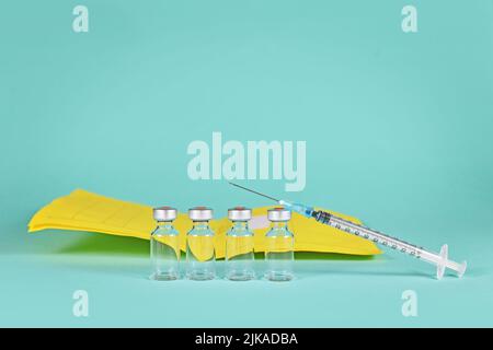 Corona Booster-Impfstoff-Konzept mit 4 Vials mit Spritzen und Impfzertifikat im Hintergrund mit Kopierraum Stockfoto