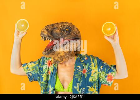 Frau in Dinosaurier-Maske zeigt frische orange Scheiben.gesundes Essen, kopieren Raum Stockfoto