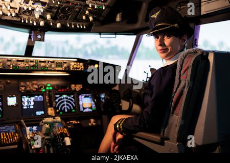 Porträt der Frau Copilot in Uniform fliegenden Flugzeug Jet aus dem Cockpit mit Bedienfeld-Befehl und Armaturenbrett-Tasten, Lufttransport. Frau mit Schalter und Hebel mit Radarnavigation. Stockfoto