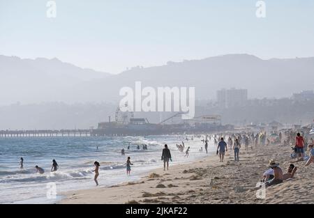 Los Angeles, 12. Juli 2022: Die Menschen genießen die Nachmittagssonne am Venice Beach, Los Angeles, mit nebligen Hügeln im Hintergrund Stockfoto