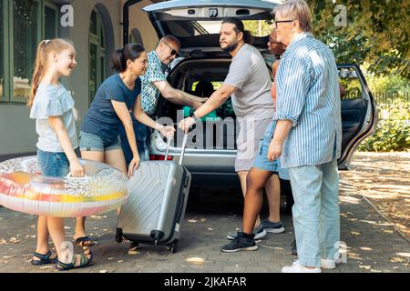 Verschiedene Menschen, die Gepäck in den Kofferraum laden, reisen mit multiethnischen Familien und Freunden in den Urlaub am Meer. Abfahrt auf Abenteuer Reise mit Gepäck, Koffer und aufblasbar. Stockfoto