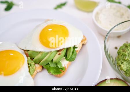 Gesundes Frühstück oder Snack: Avocado in Scheiben geschnitten und Spiegelei auf geröstetem Brot Stockfoto