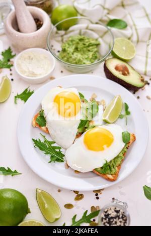 Gesundes Frühstück oder Snack: Avocado in Scheiben geschnitten und Spiegelei auf geröstetem Brot Stockfoto
