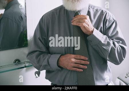 Eleganter älterer Mann mit weißem Bart, der seine Krawatte justiert Stockfoto