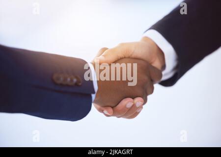 Junge Gläubige, wir halten keine pleite Haltung. Zwei unkenntliche Geschäftsleute schütteln die Hände vor einem verschwommenen weißen Hintergrund. Stockfoto