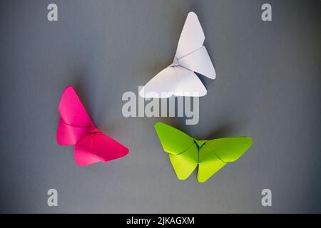 Grün, rosa und weiß Papier Schmetterling Origami isoliert auf einem weißen grauen Hintergrund. Stockfoto