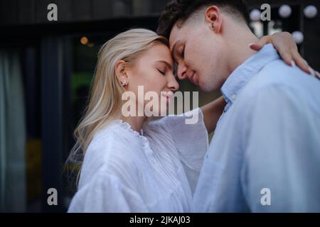 Junges Paar in der Liebe Kuscheln und Küssen im Freien auf der Terrasse, Wochenende in winzigen Haus auf dem Land, nachhaltiges Leben. Stockfoto