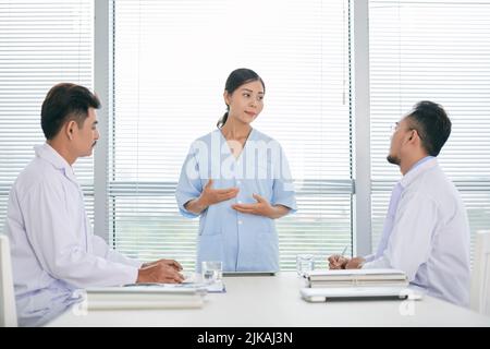 Hübsche Ärztin, die vor Kollegen spricht Stockfoto