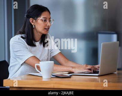 Eine junge Frau, die Kaffee getrunken und in einem modernen Büro gearbeitet hat. Stockfoto