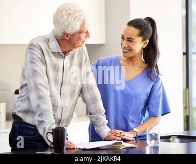 Diese Unterlagen sichern Ihre Zukunft. Eine Krankenschwester, die mit ihrer älteren Patientin über die Unterlagen geht. Stockfoto