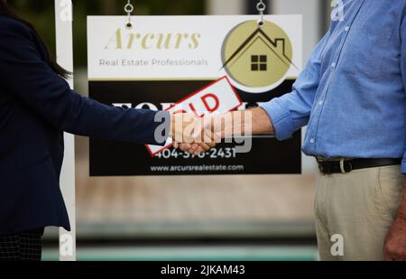 Abschluss des Deals mit einem Handschlag. Zugeschnittenes Porträt einer unkenntlich-weiblichen Immobilienmaklerin und ihres männlichen Kunden, der sich vor einem die Hände schüttelte Stockfoto