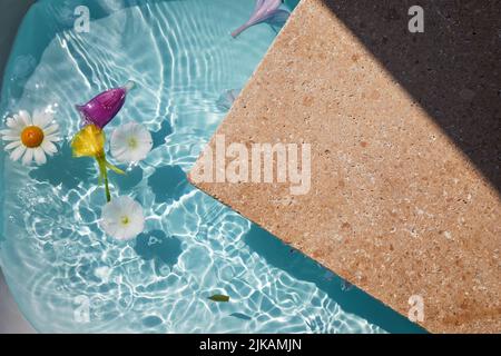 Produktförderung Beauty Kosmetik Schaufenster. Travertin Stein Display mit Blumen im Wasser. Stockfoto