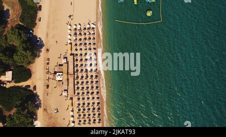 Der schmale Sandstrand von Glarokavos aus der Vogelperspektive. Liegestühle und Sonnenschirme können gemietet werden. Sommerferien Konzept. Hochwertige Fotos Stockfoto