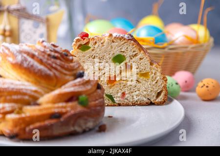 Craffin (Cruffin) mit Rosinen und kandierten Früchten. Traditionelles Osterbrot Kulich und bemalte Eier auf grauem Hintergrund. Osterferien. Nahaufnahme, se Stockfoto
