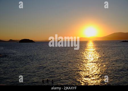 Touristen schwimmen bei Sonnenuntergang auf der Insel Hydra in Griechenland im Sommer Stockfoto