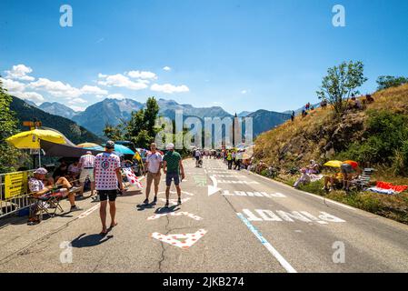 Radsportfans, die die Strecke auf der Alpe d'Huez während der Tour de France 2022 auffahren, und die Fahrer, die durch die Tour fahren Stockfoto