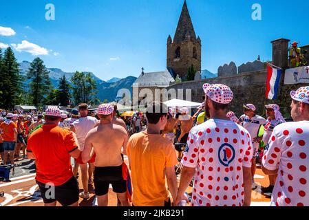 Radsportfans, die die Strecke auf der Alpe d'Huez während der Tour de France 2022 auffahren, und die Fahrer, die durch die Tour fahren Stockfoto