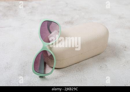 Damen trendige schwarze Sonnenbrille in türkisfarbenem Rahmen auf grauem Hintergrund. Stillleben in minimalem Stil. Sonnenbrillen im Sonderangebot. Sommerangebot. Speicherplatz kopieren Stockfoto