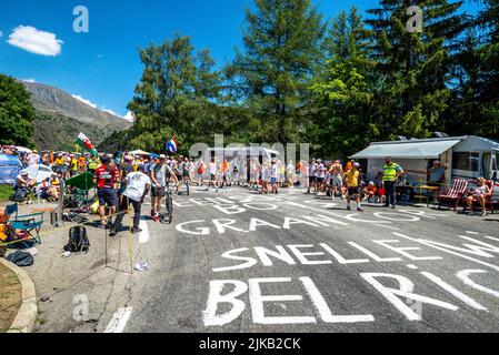 Radsportfans, die die Strecke auf der Alpe d'Huez während der Tour de France 2022 auffahren, und die Fahrer, die durch die Tour fahren Stockfoto