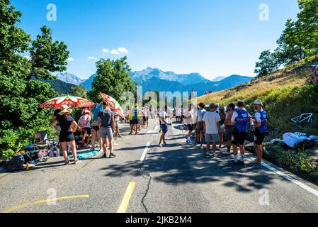 Radsportfans, die die Strecke auf der Alpe d'Huez während der Tour de France 2022 auffahren, und die Fahrer, die durch die Tour fahren Stockfoto