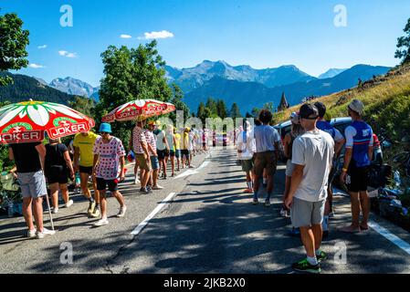 Radsportfans, die die Strecke auf der Alpe d'Huez während der Tour de France 2022 auffahren, und die Fahrer, die durch die Tour fahren Stockfoto