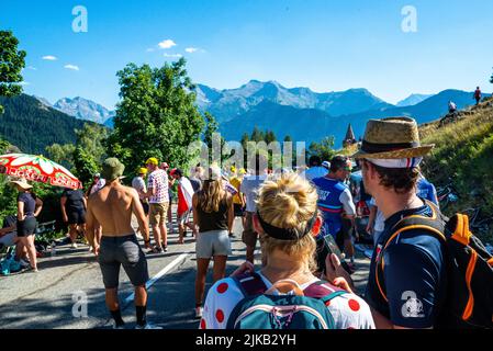 Radsportfans, die die Strecke auf der Alpe d'Huez während der Tour de France 2022 auffahren, und die Fahrer, die durch die Tour fahren Stockfoto