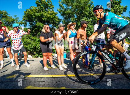 Radsportfans, die die Strecke auf der Alpe d'Huez während der Tour de France 2022 auffahren, und die Fahrer, die durch die Tour fahren Stockfoto