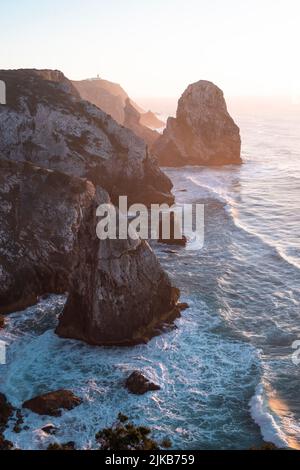 Felsen und Meeresbrandung in Miradouro da Praia do Caneiro bei einem schönen Sonnenuntergang, Atlantik, Portugal. Stockfoto